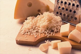 Grated cheese, Maasdam, on a cutting board, grater and cheese knife, close-up, no people