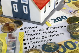 Symbolic image of building insurance: close-up of contract documents, a model house, euro banknotes