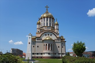 Church with golden domes against a clear sky, embedded in urban greenery, Orthodox Cathedral of St