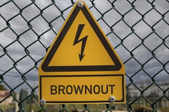 Symbolic image: The word Brownout is written under a sign that usually warns of high voltage