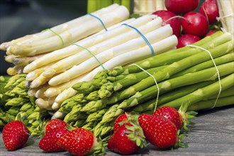 Green asparagus, white asparagus and fresh strawberries decorated on a rustic wooden table