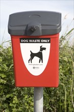 Close up of red litter bin for dog waste only, Suffolk, England, United Kingdom, Europe