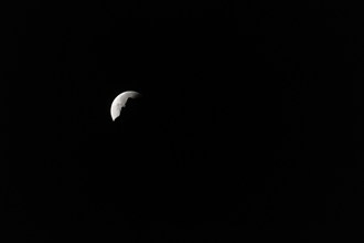 The moon disappears behind a mountain silhouette, taken in the Swiss mountains, Switzerland, Europe