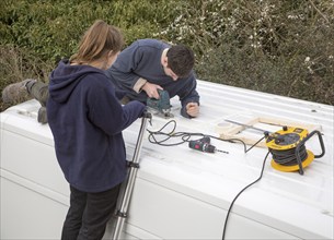 Cutting through roof of white metal camper van conversion to install ventilation window, UK