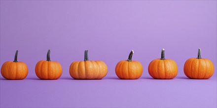 Small orange pumpkins in a row on violet background. Generative Ai, AI generated