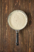 A creamy mixture in a skillet, showcasing a smooth texture and slight bubbles of bechamel sauce.