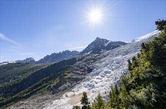 View of glacier Glacier des Bossons with sun star, behind summit of Aiguille du Midi, Chamonix,