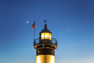 Upper segment of an illuminated lighthouse at night, black and white lighthouse, called 'Kleiner