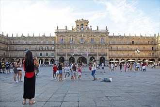 Street artists and children playing in the Plaza Mayor, behind the town hall, Salamanca, province