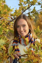 Portrait of young beautiful smiling woman, 30 years old, outdoors in forest with autumn colors in