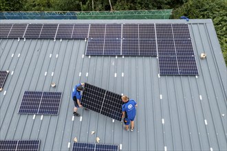 Installation of solar modules on the roof of a barn on a farm, over 240 photovoltaic modules are