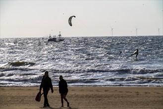 Kitesurfers and shrimp boats off the coast of Scheveningen, walkers on the beach, The Hague,