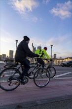 Skyline of the city centre of Frankfurt am Main, cyclist on the Ignatz-Bubis-Bridge, dusk, river