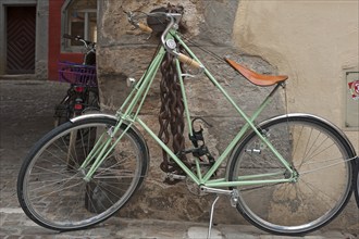 Modern bicycle chained to a house wall, heavy iron chain with lock on the wall behind, Regensburg,