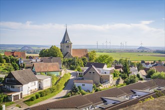 A peaceful village with a church in the foreground and wind turbines in the distance, Harz