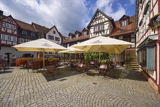 Outdoor area of a restaurant with parasols, tables and chairs on the market square in Michelstadt,