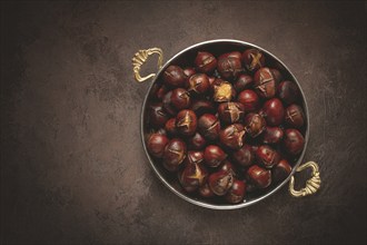 Roasted chestnuts, in a wooden plate, top view, homemade, no people