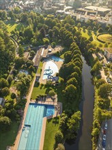 Close-up of an outdoor swimming pool and water park area surrounded by manicured green spaces and