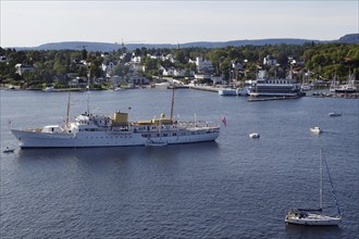 Coast with ships and boats, surrounded by houses and hills full of trees, the yacht of the royal