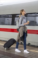 Young woman on the railway track while a train arrives