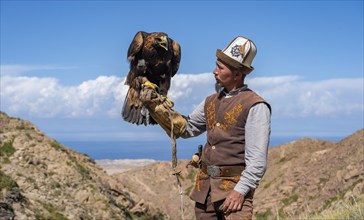 Traditional Kyrgyz eagle hunter with eagle in the mountains, near Kysyl-Suu, Kyrgyzstan, Asia