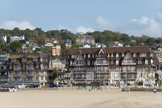 Traditional half-timbered houses in a coastal town in front of a wooded hill, Trouville-sur-Mer,