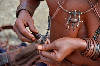 Himba woman cleaning her traditional jewellery, Opuwo, Kaokoland, Kunene, Namibia, Africa