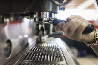 Symbol photo on the subject of a sieve coffee machine. A woman makes a coffee at a coffee machine