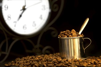 Steel cup of coffee and clock at background