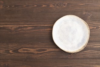 Empty blue and white ceramic plate on brown wooden background. Top view, copy space, flat lay