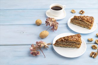 Walnut and hazelnut cake with caramel cream, cup of coffee on blue wooden background. side view,