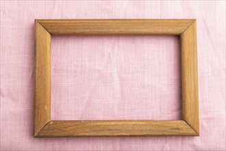 Wooden frame on smooth pink linen tissue. Top view, flat lay, natural textile background and