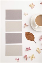 Composition with gray paper business card, brown beech autumn leaves, hydrangea flowers and cup of