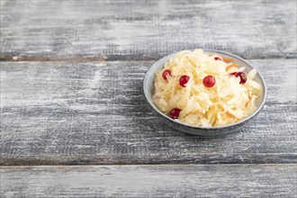 Sauerkraut, marinated cabbage on a blue ceramic plate on a gray wooden background. Side view, close