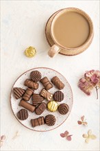 Chocolate candies with cup of coffee and hydrangea flowers on a white concrete background. top