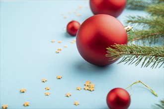 Christmas or New Year composition. Decorations, red balls, fir and spruce branches, on a blue paper