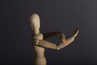 Wooden mannequin shows obscene gesture fuck off with hands on gray background. protest, riot,