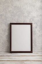 Brown wooden frame mockup on gray concrete background. Blank, vertical orientation, still life,