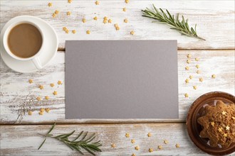 Gray paper sheet mockup with cup of coffee and cake on white wooden background. Blank, top view,