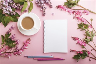 Purple lilac and bleeding heart flowers and a cup of coffee with notebook and colored pencils on