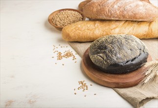 Different kinds of fresh baked bread on a white wooden background. side view, close up, copy space