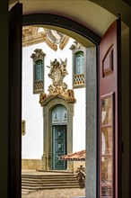 Baroque church front seen through the window of an old colonial-style house in the city of Mariana