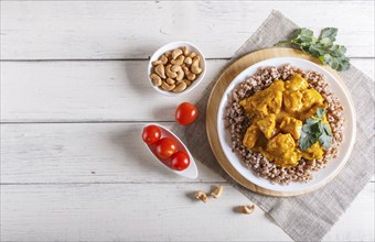 Buckwheat with chicken curry sauce with cashew on white wooden background. top view, copy space