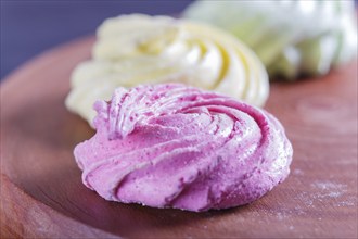 Colored meringues on wooden board, selective focus, close up