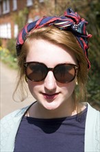 Model released head and shoulders portrait of teenage girl wearing sunglasses and head scarf