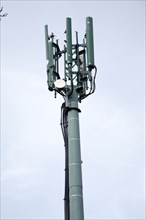 Mobile phone relay transmitter tower seen against blue cloudy sky, UK