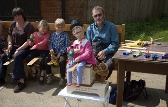 Man operating a traditional wooden jig doll dancer during a country folk event at Shottisham,