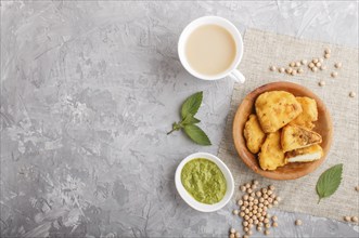 Traditional indian food paneer pakora in wooden plate with mint chutney on a gray concrete