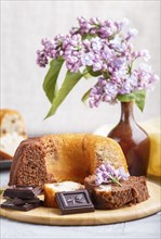 Cakes with raisins and chocolate and a cup of coffee. lilac flowers on a gray concrete background,