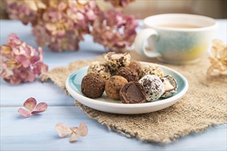 Chocolate truffle candies with cup of coffee on a blue wooden background and linen textile. side